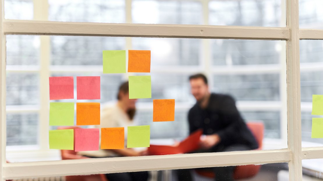 [Translate to English:] Studierende an einer Wand mit bunten Post-It Zetteln